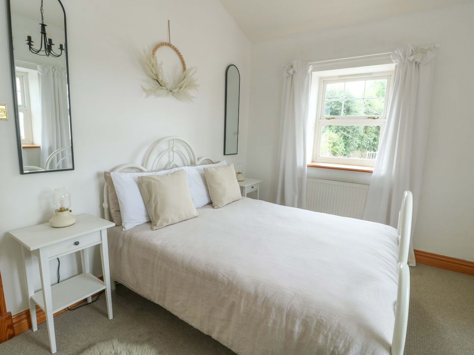 A bedroom with a bed and bedside table at Bwthyn Clai in Llangefni
