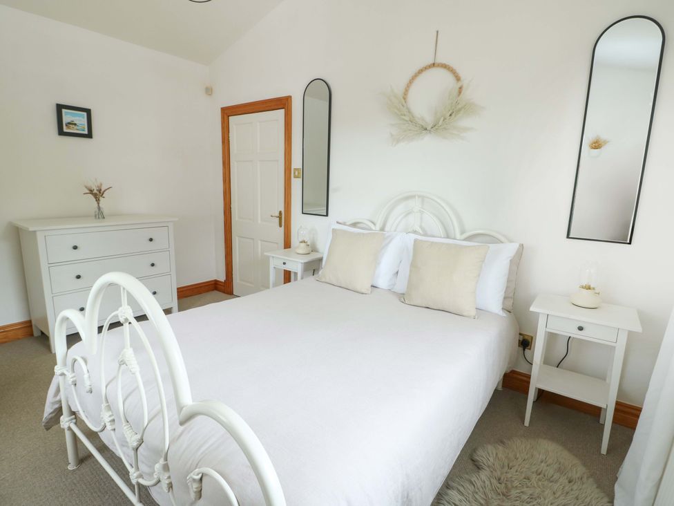 A bedroom with a bed and dresser at Bwthyn Clai in Llangefni