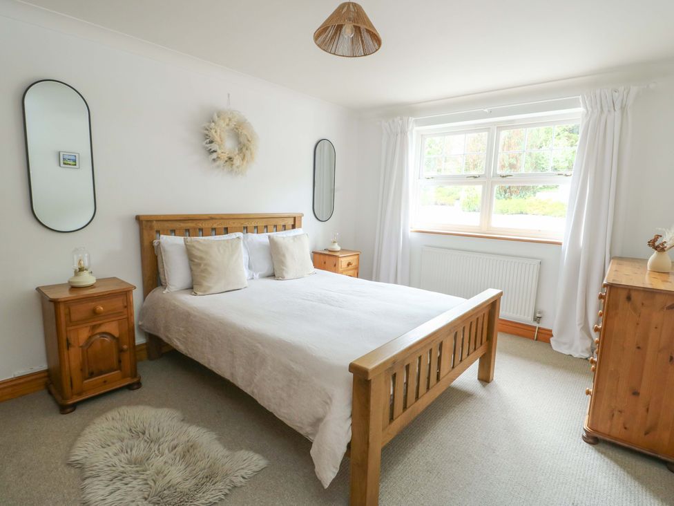 A bedroom with a bed and bedside tables at Bwthyn Clai in Llangefni