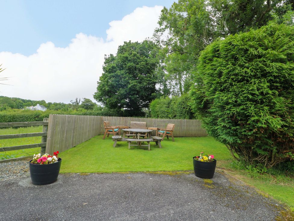 A garden with a wooden table and chairs at Bwthyn Clai in Llangefni