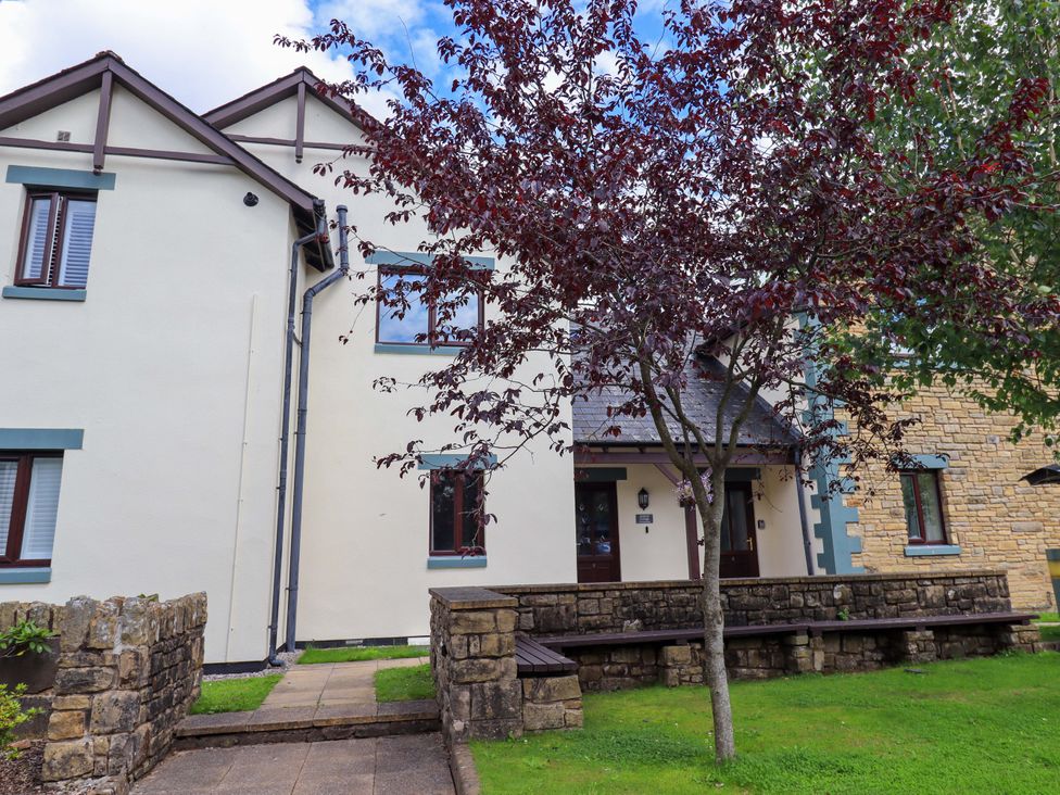 An exterior view of a building with benches and a tree at Mallard Cottage in Penrith