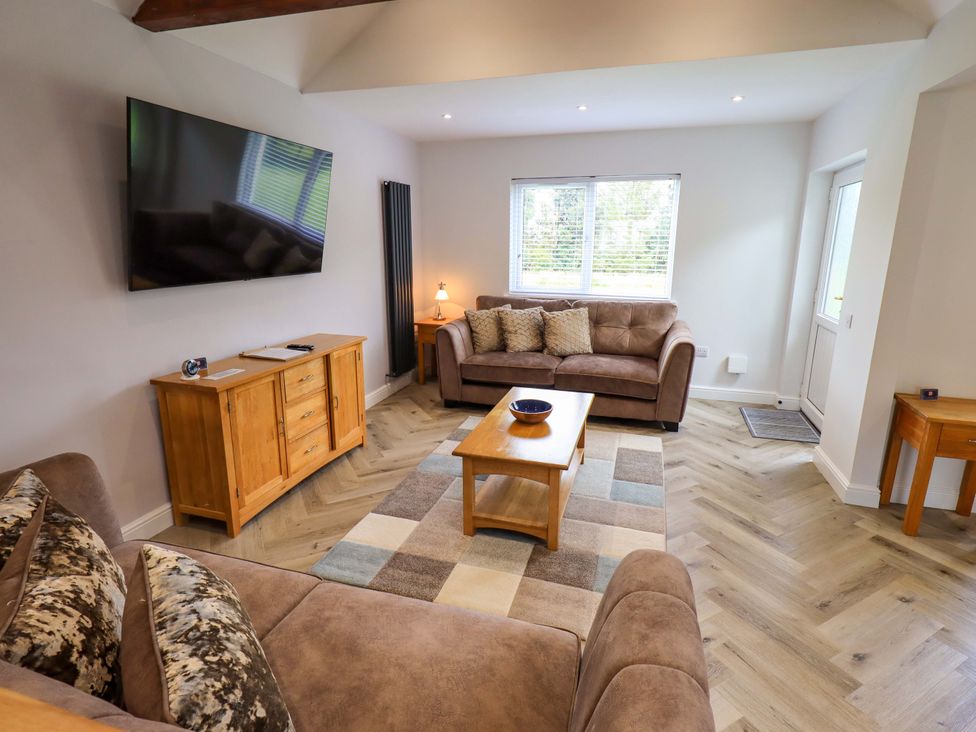 A living room with a television, sofa, and coffee table at Mallard Cottage in Penrith