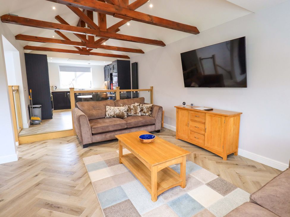 A living room with a sofa, coffee table, and television at Mallard Cottage in Penrith