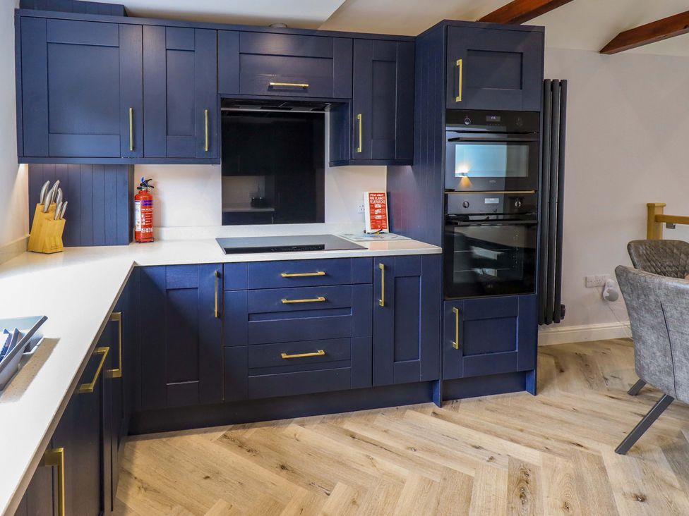 A kitchen with blue cabinets and built-in appliances at Mallard Cottage Penrith