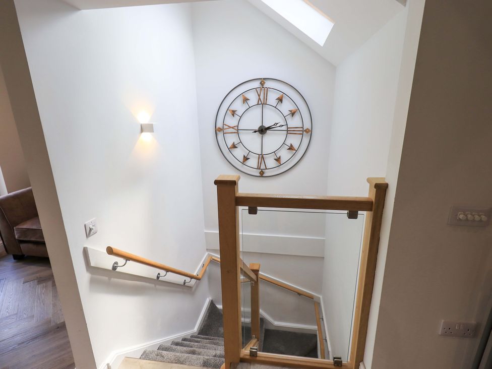 A staircase with a clock on the wall at Mallard Cottage in Penrith