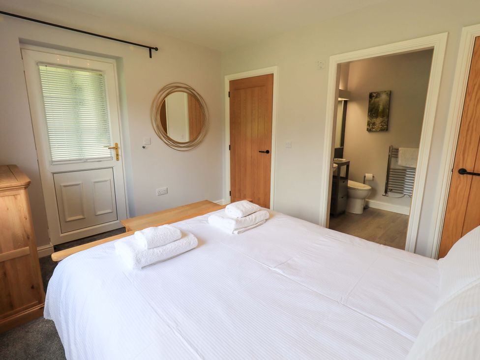 A bedroom with a bed and access to a bathroom at Mallard Cottage in Penrith