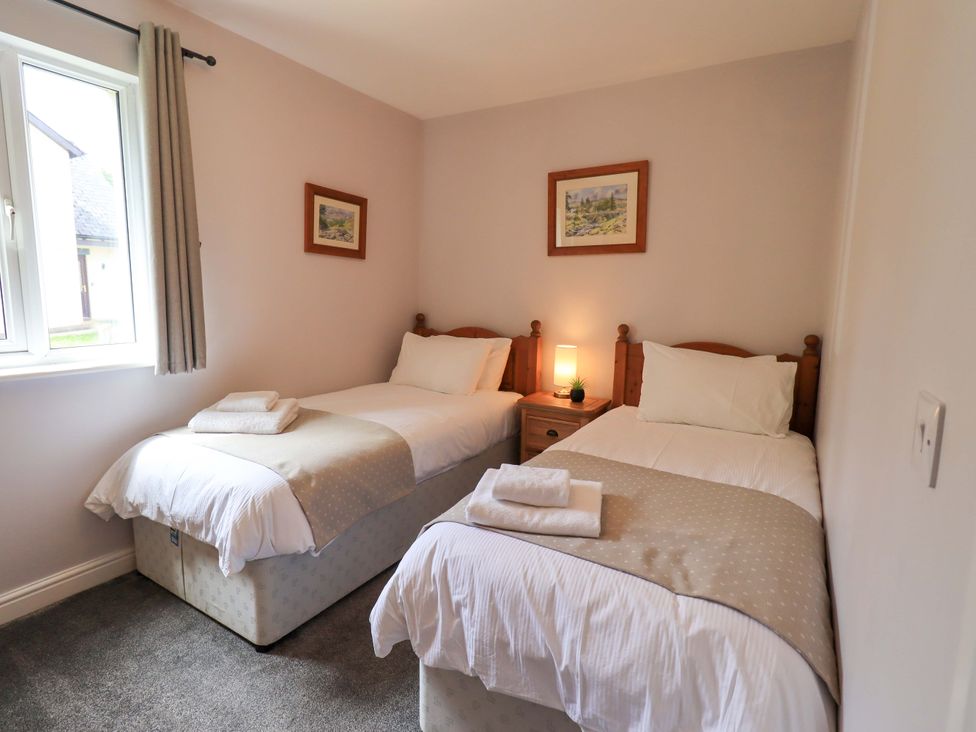 A bedroom with two single beds and a nightstand at Mallard Cottage in Penrith