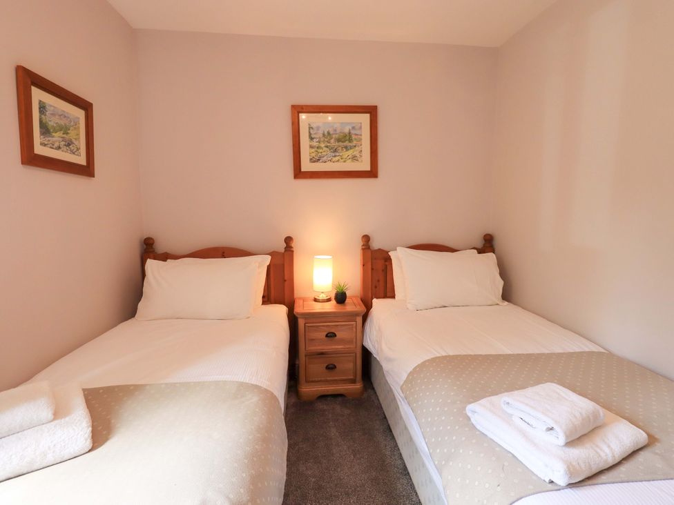 A bedroom with two single beds and a nightstand at Mallard Cottage in Penrith