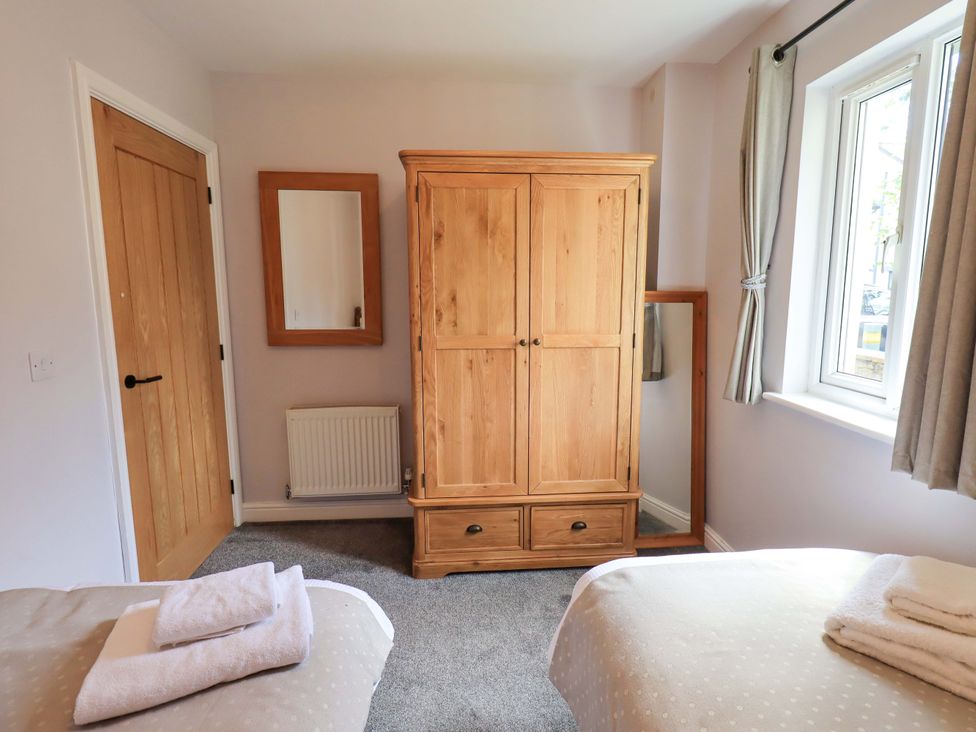 A bedroom with a wardrobe, a mirror, and two beds at Mallard Cottage in Penrith