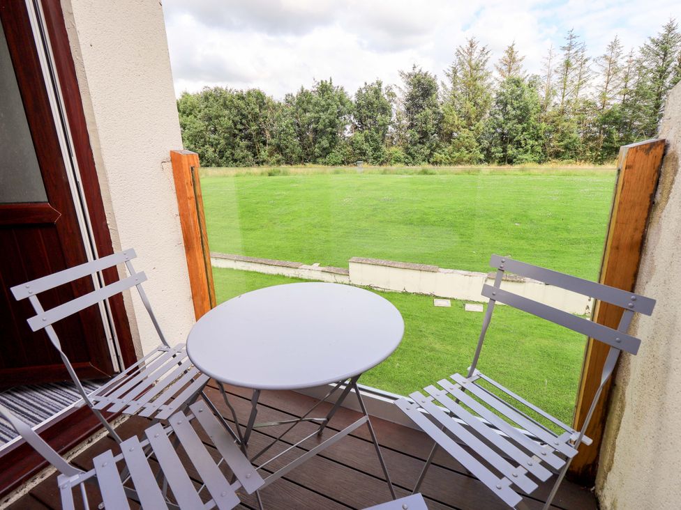 A balcony with a table and chairs overlooking grass at Mallard Cottage Penrith