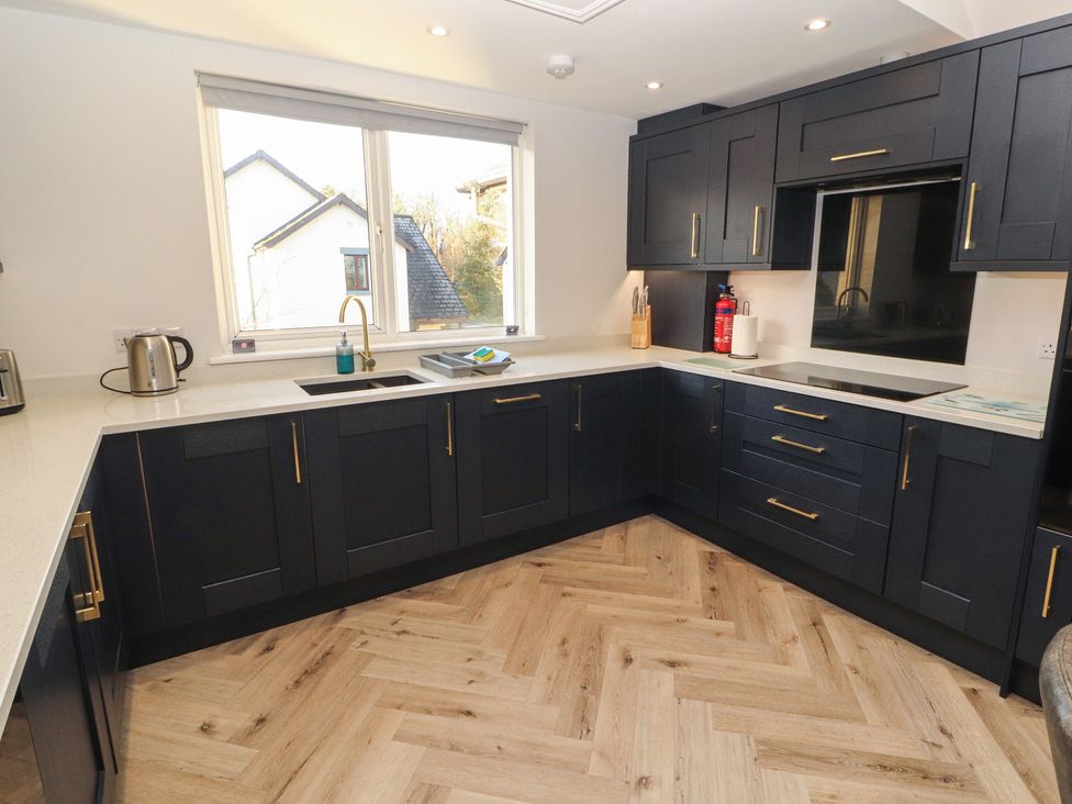 A kitchen with dark cabinets and a window at Mallard Cottage in Penrith