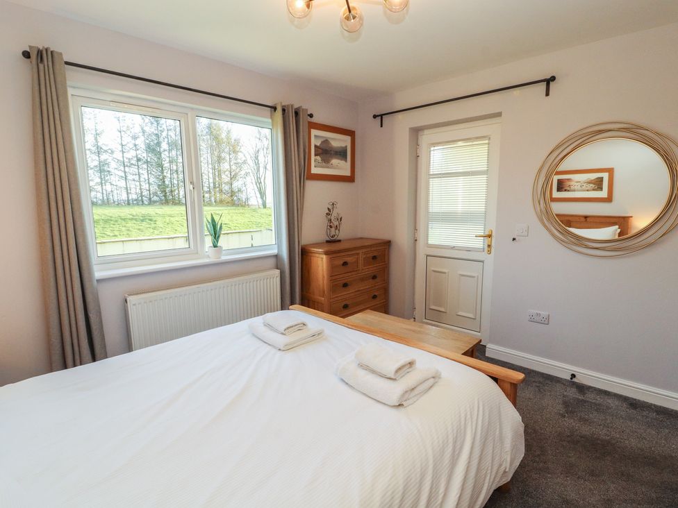 A bedroom with a large bed and dresser at Mallard Cottage in Penrith