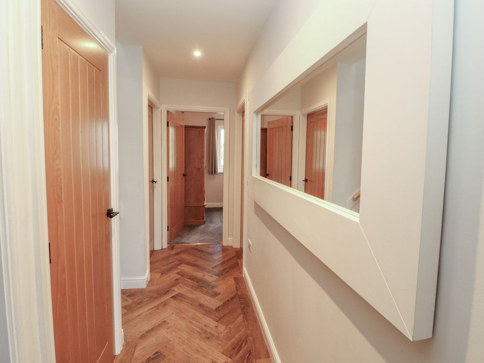 A hallway with doors and a mirror at Mallard Cottage in Penrith