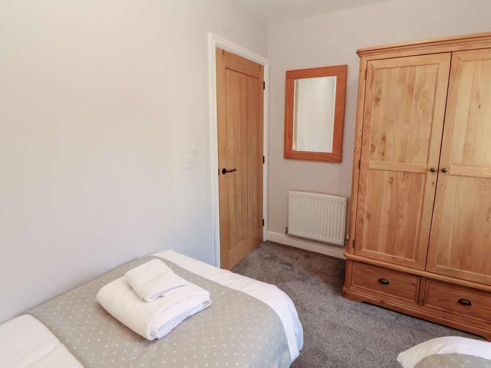 A bedroom with a bed and wardrobe at Mallard Cottage in Penrith