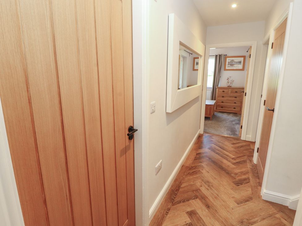 A hallway with a door and a mirror at Mallard Cottage Penrith