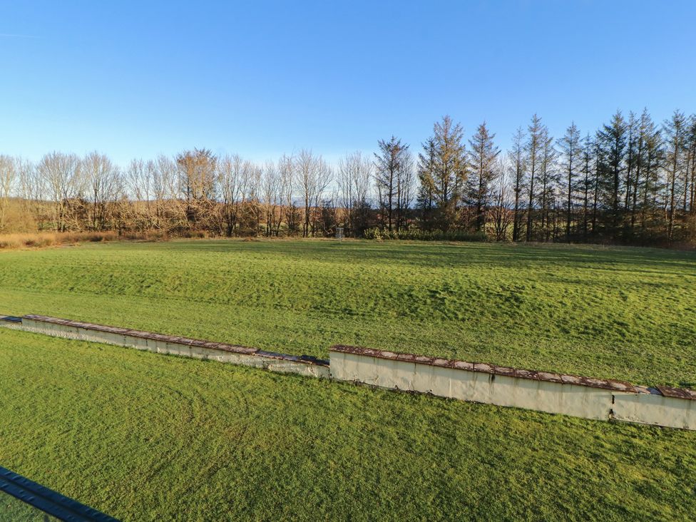 A grassy area with trees in the background at Mallard Cottage Penrith