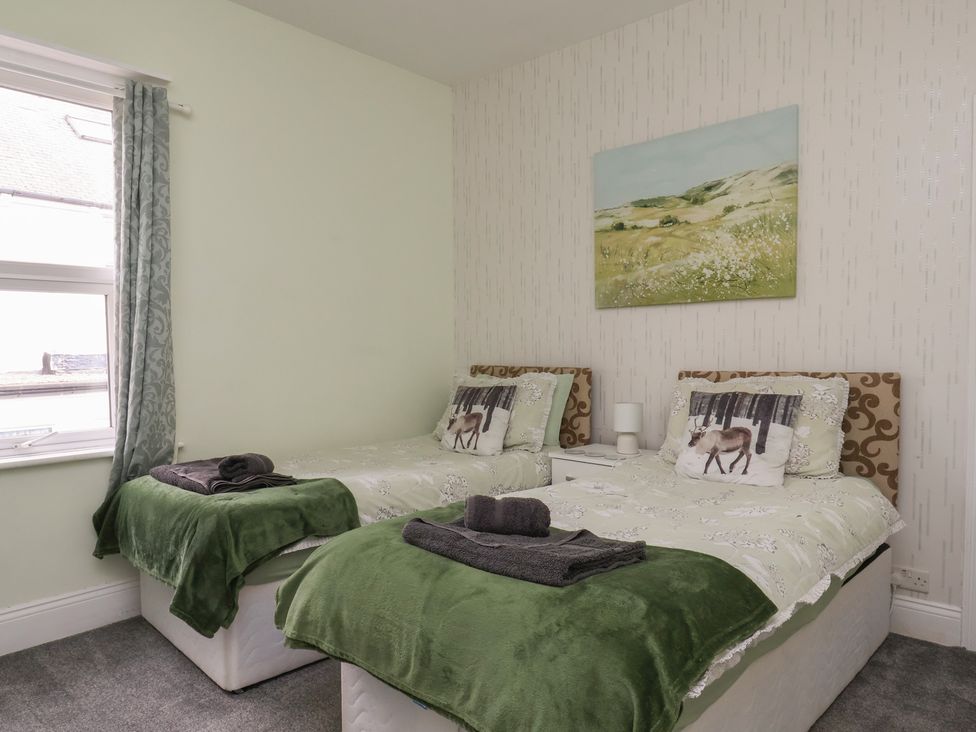 A bedroom with two beds and a painting at 35 Moorland Road, Scarborough