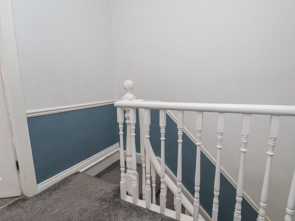 A staircase with a handrail and blue wall at 35 Moorland Road, Scarborough
