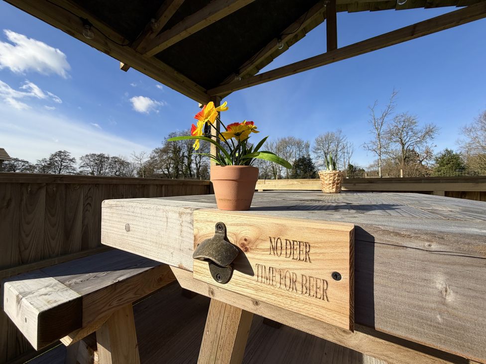 An outdoor seating area with a wooden table and flower pot at No Deer in Ashbourne