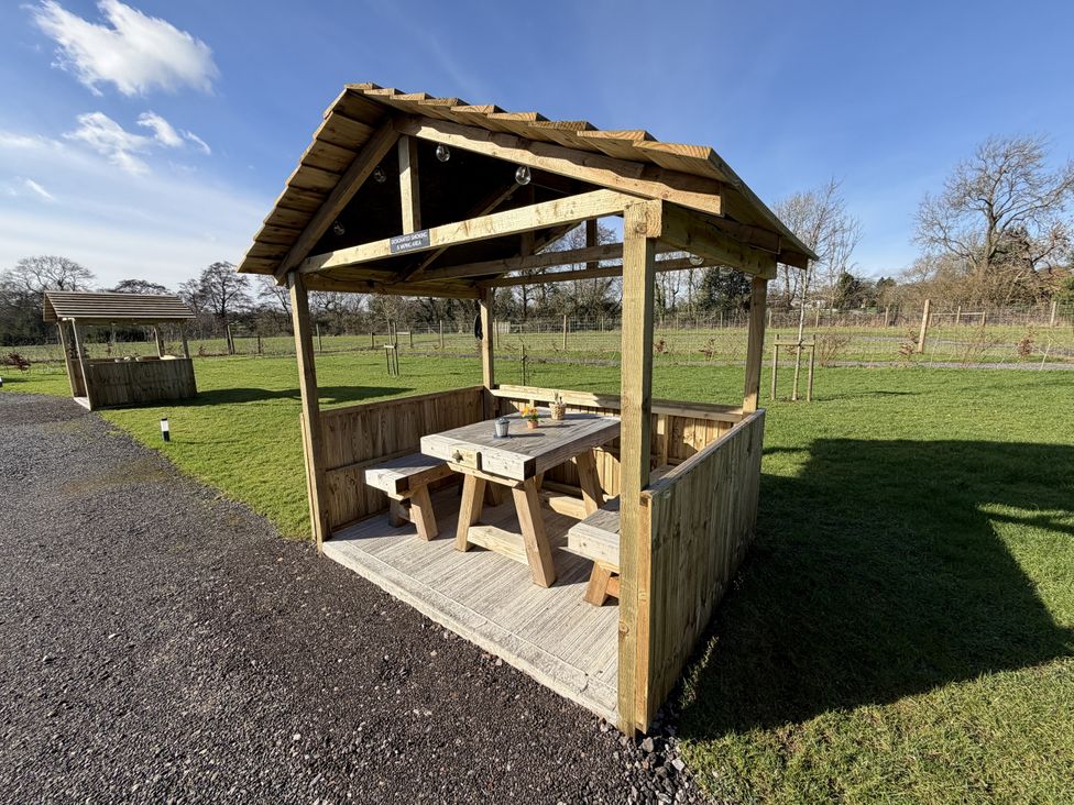 A wooden shelter with a table and benches at No Deer Ashbourne