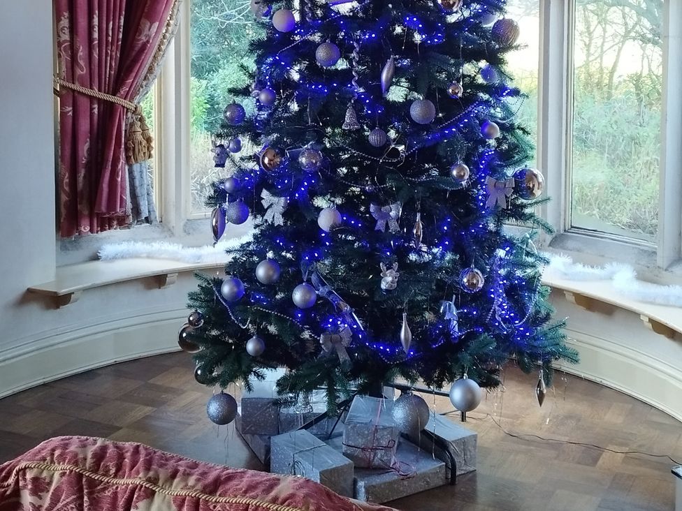 A Christmas tree with presents in a living room at Highcliffe Manor in Flamborough