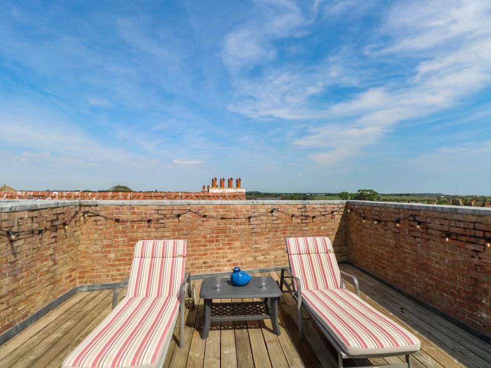A roof terrace with deck chairs and a table at Skylark in Southwold