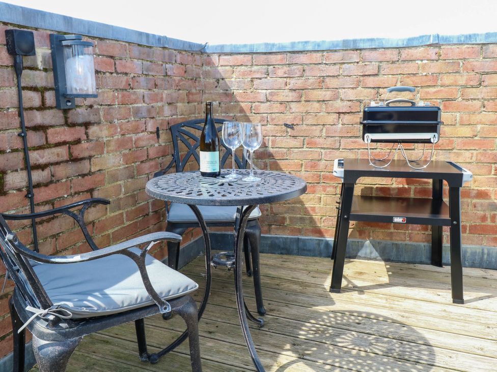 An outdoor area with a table, chairs, wine, and a grill at Skylark in Southwold