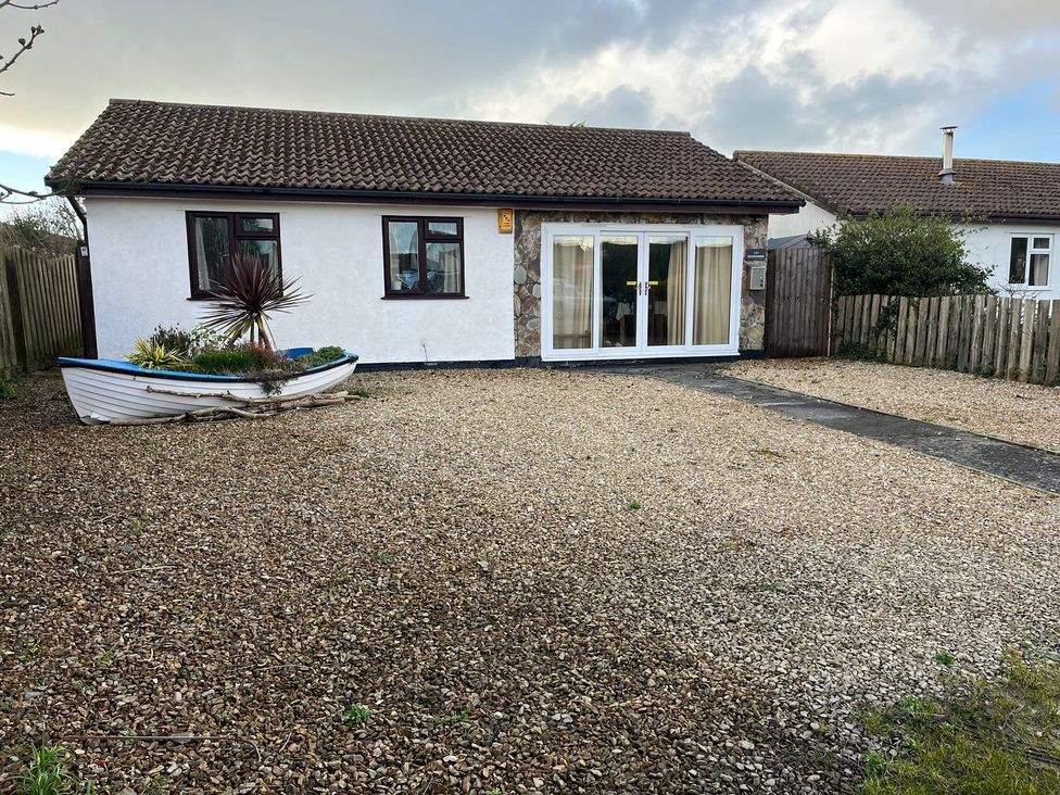 A house with a gravel driveway and a decorative boat at Beachcombers in St Merryn