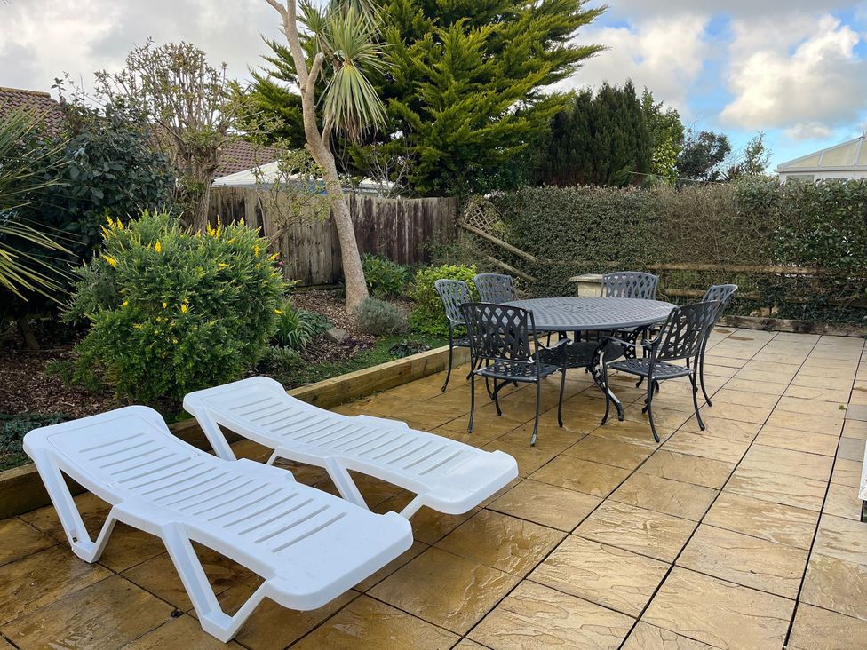 A garden with a dining table and chairs and two lounge chairs at Beachcombers in St Merryn