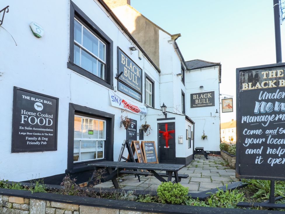An outdoor pub with signs and seating at The Black Bull in 