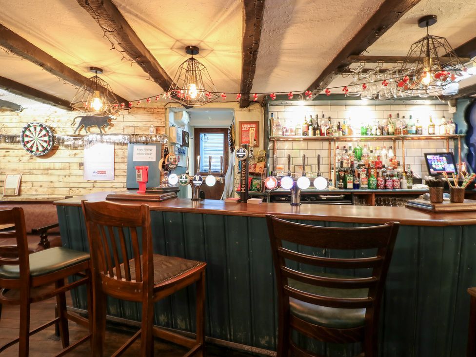 A bar with stools and shelves filled with bottles at Bedroom 1