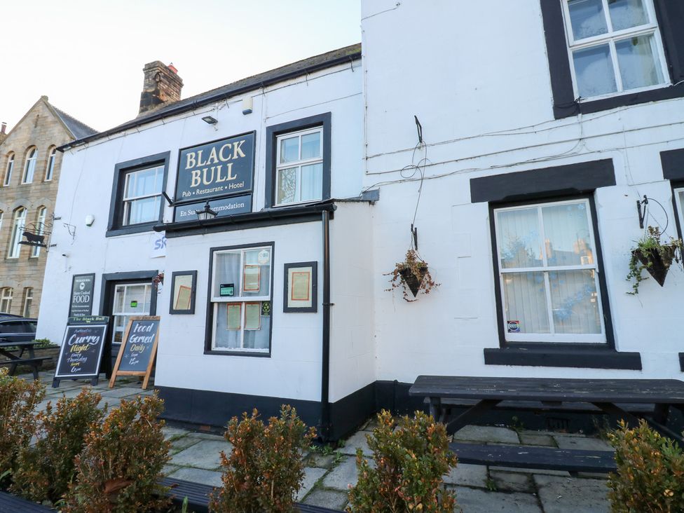 Exterior view of pub and restaurant named Black Bull with signage and outdoor seating