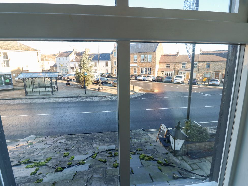 A view from a window showing a street with cars and a bus stop