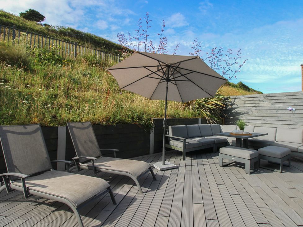 An outdoor area with deck chairs and a table at 7 Beachdown in Challaborough