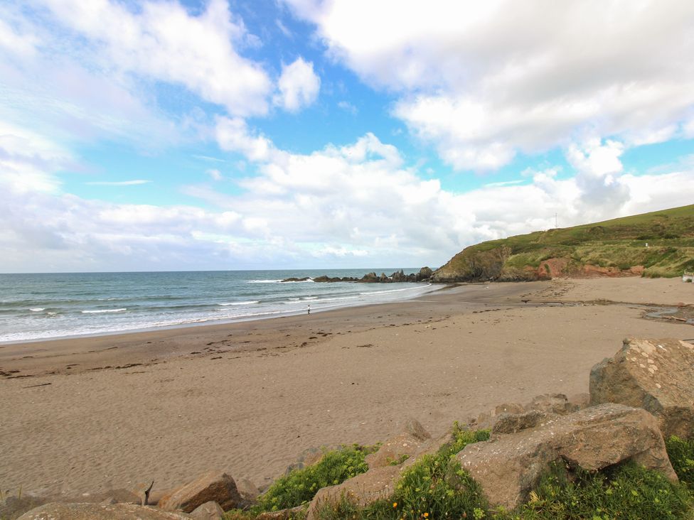 A beach with waves and rocks at 7 Beachdown in Challaborough
