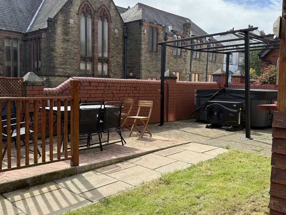 A garden with a table and chairs near a hot tub at The Furness Haven in Barrow-In-Furness