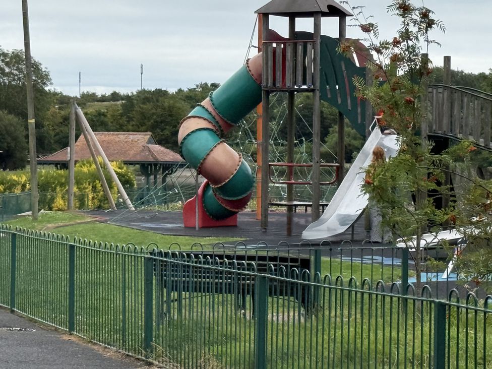 A playground with a slide and swings at The Furness Haven in Barrow-In-Furness