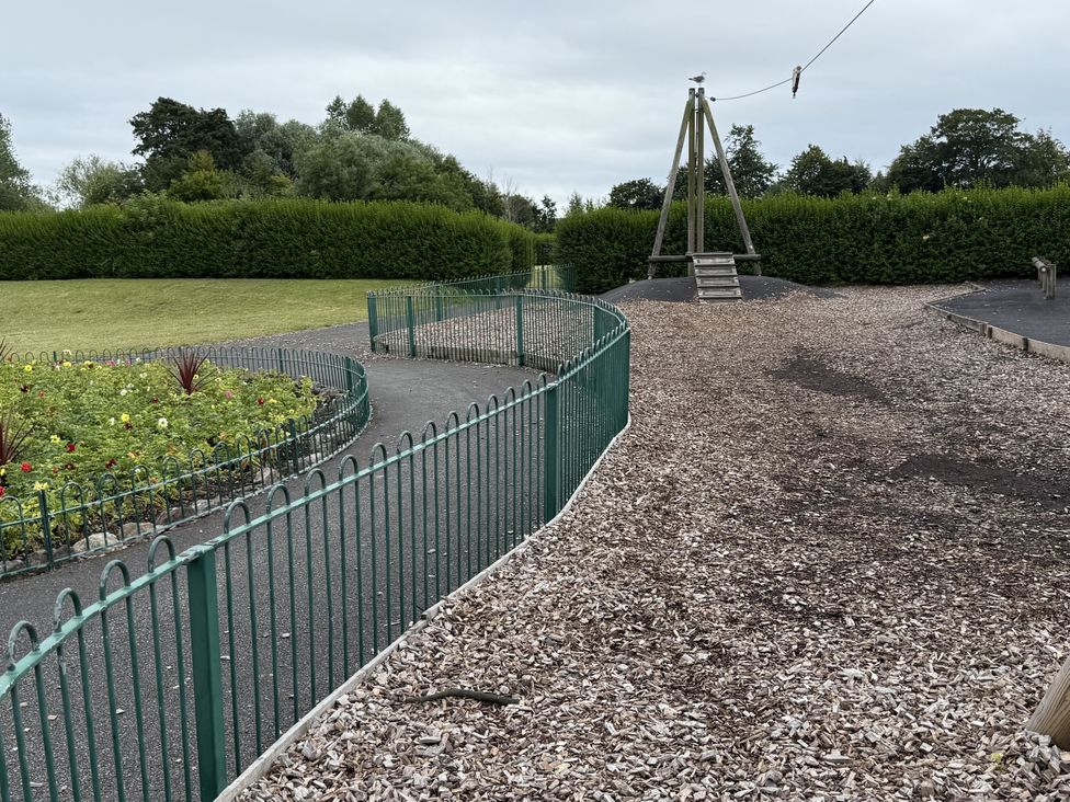 A playground area with a slide and a flower bed at The Furness Haven Barrow-In-Furness