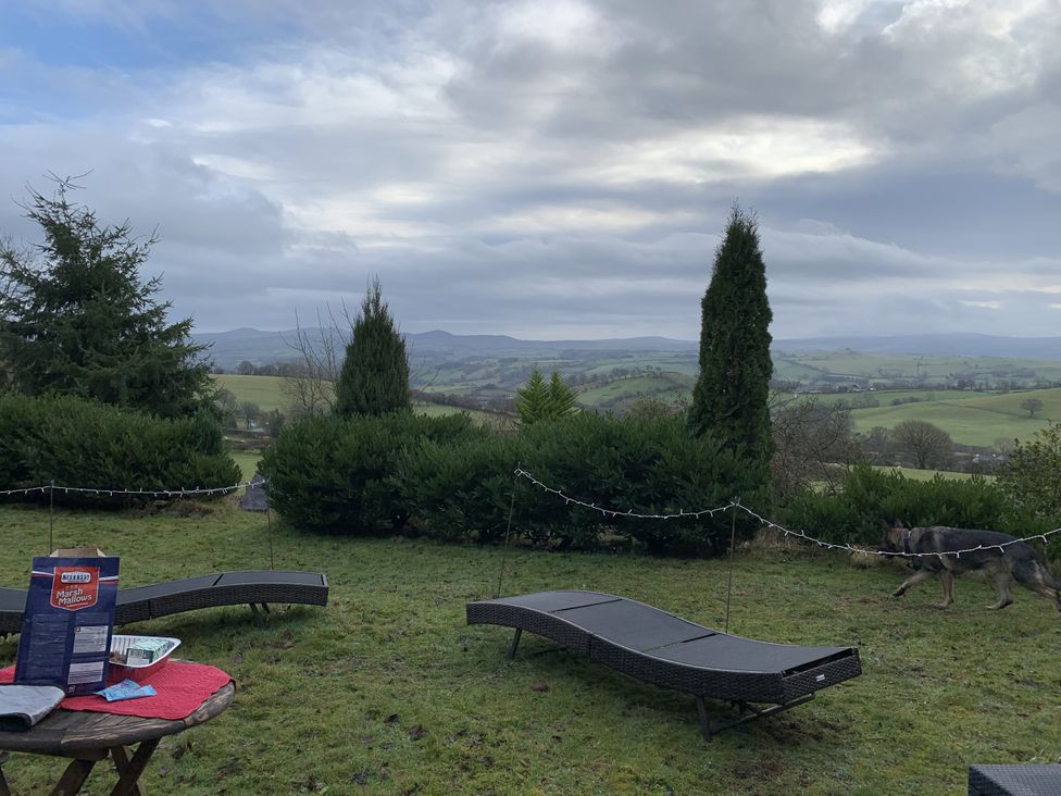 A garden with deck chairs and a table at Coach House in Clawdd-Newydd