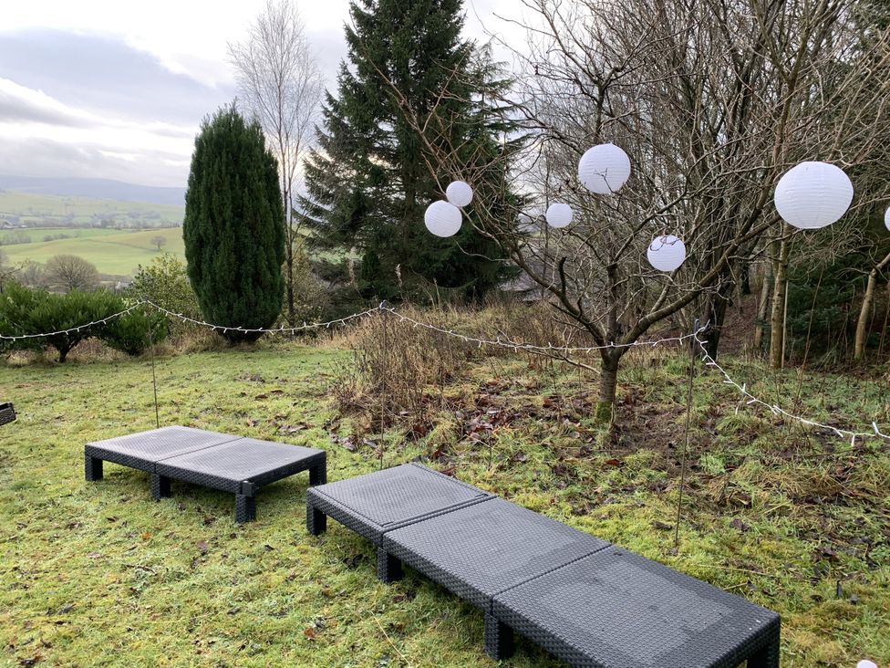 Outdoor seating with lanterns hanging in a garden at Coach House in Clawdd-Newydd