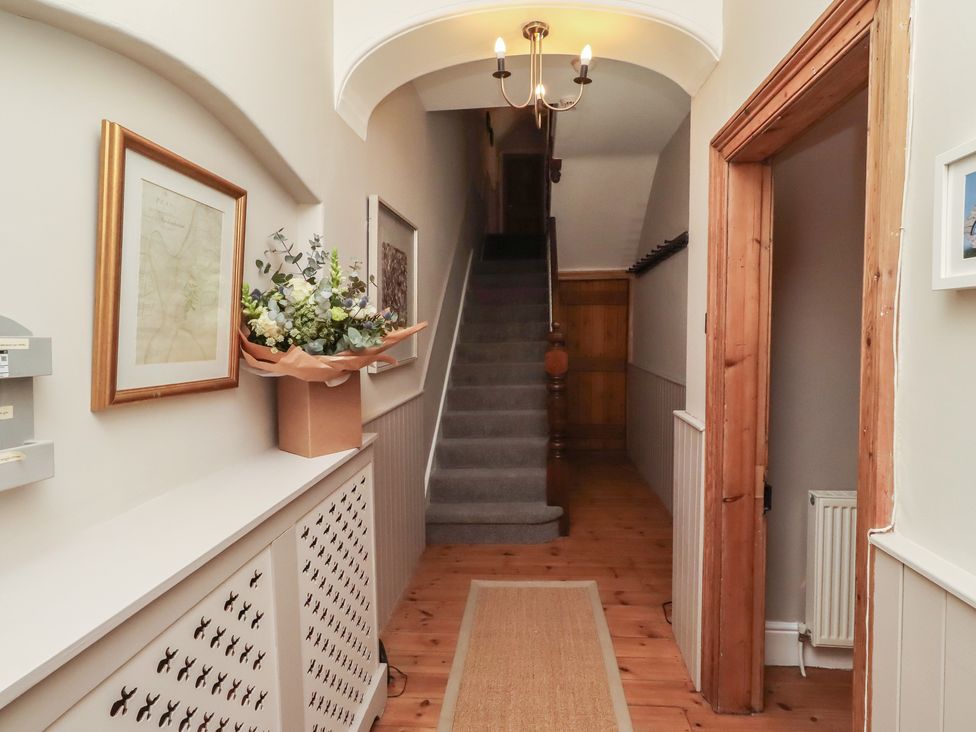 A hallway with a staircase and flower arrangement at Rose House Alnmouth