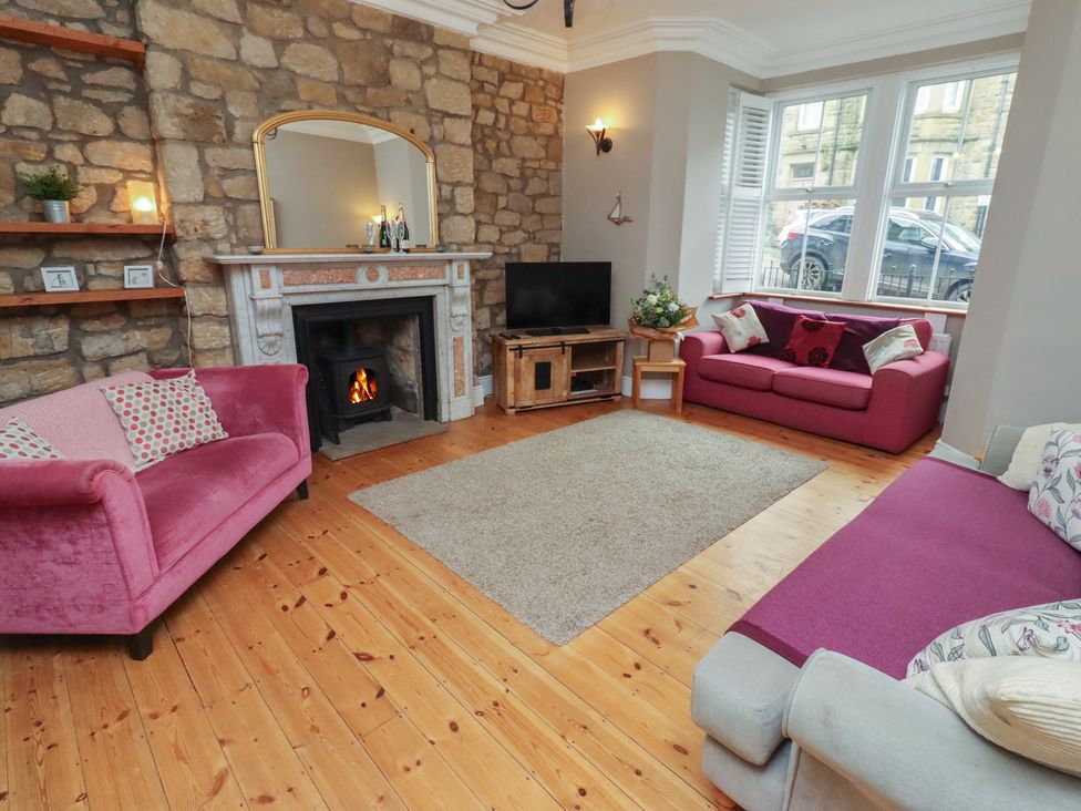 A living room with a fireplace and sofas at Rose House in Alnmouth