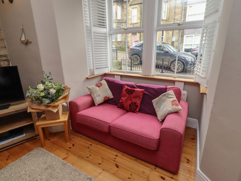 A living room with a pink sofa and television at Rose House in Alnmouth