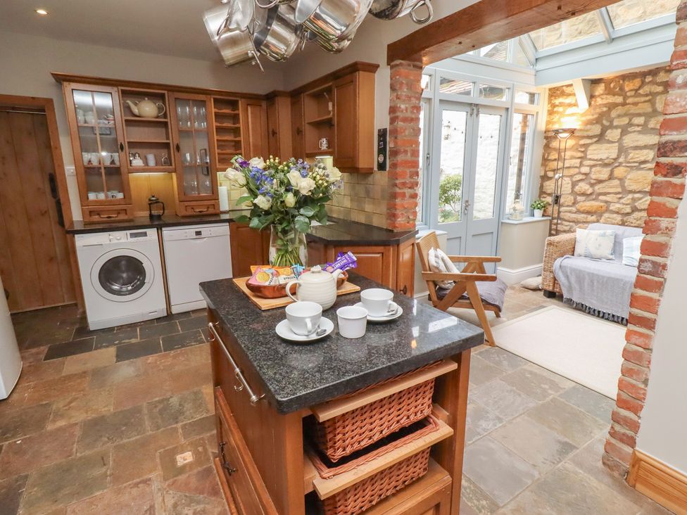 A kitchen with a washing machine and flowers on the countertop at Rose House in Alnmouth