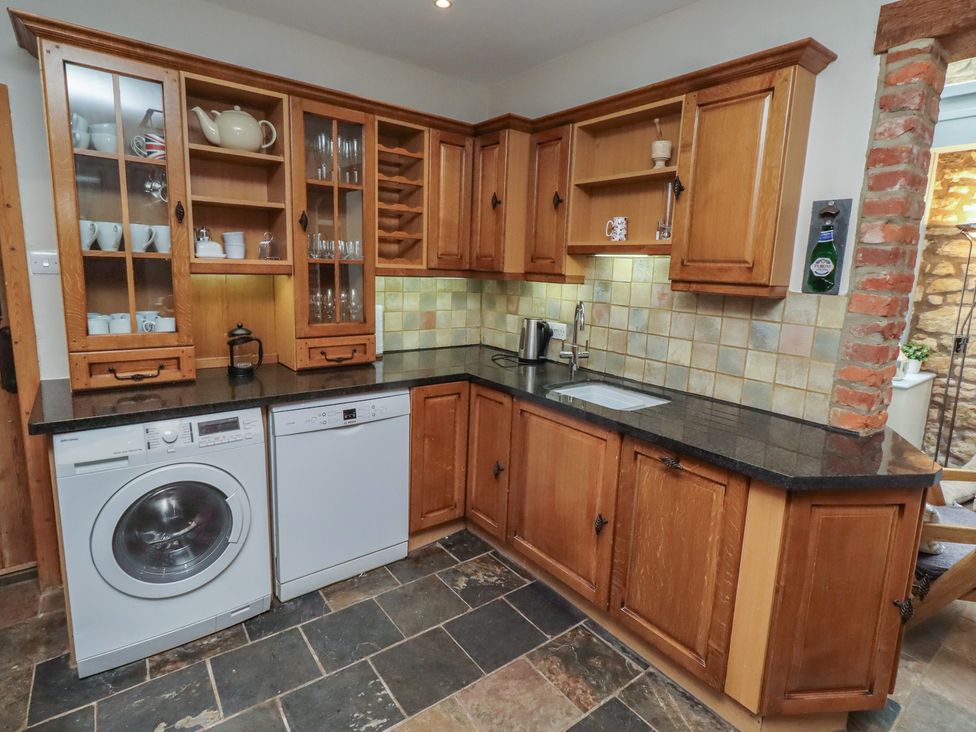 A kitchen with cabinets, washing machine, and dishwasher at Rose House in Alnmouth