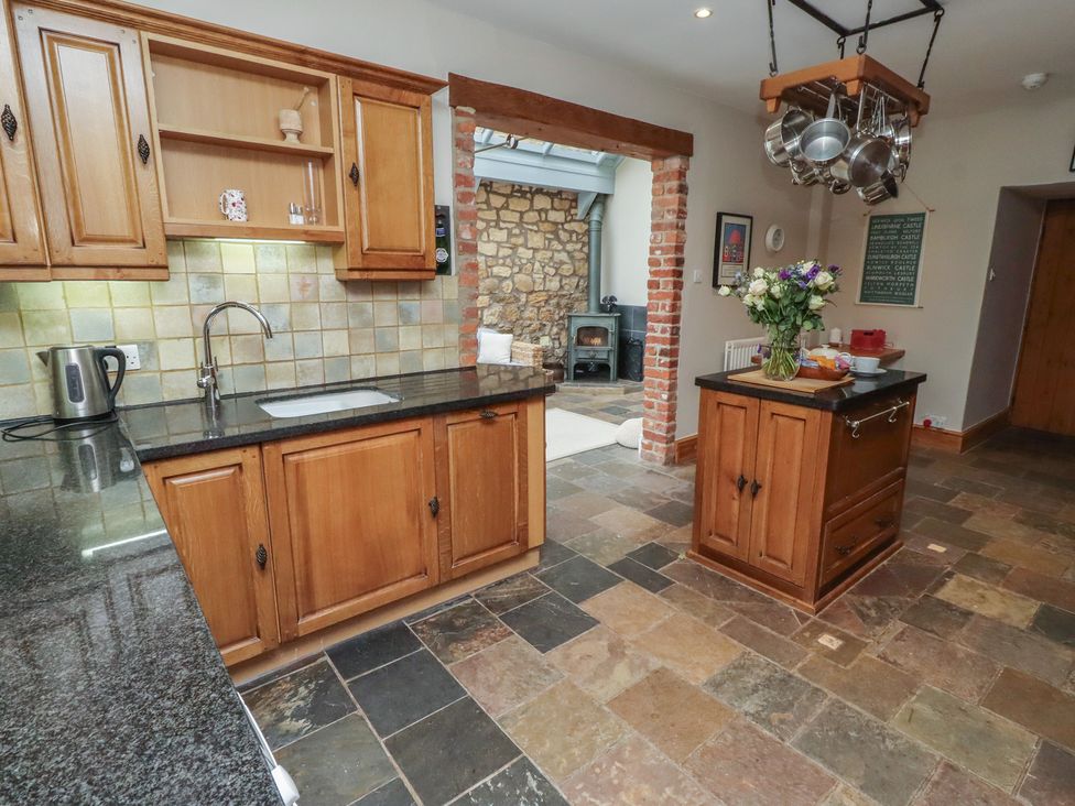 A kitchen with a sink and wooden cabinets at Rose House in Alnmouth