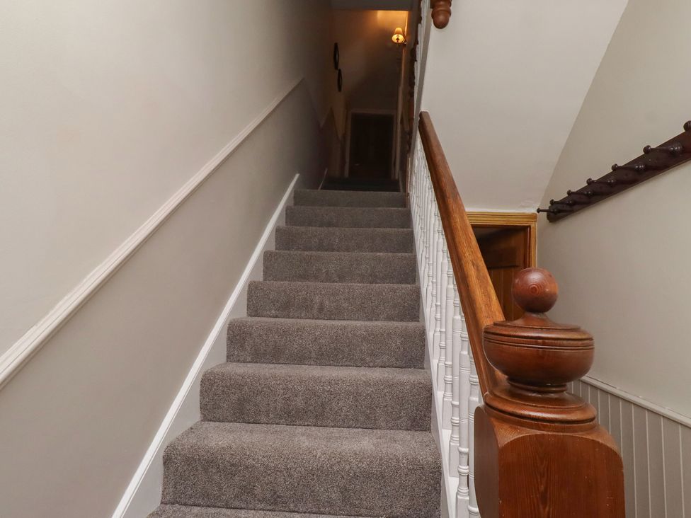 A staircase with a handrail and light fixture at Rose House in Alnmouth