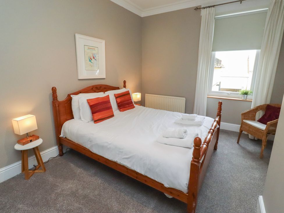 A bedroom with a bed and a chair at Rose House in Alnmouth