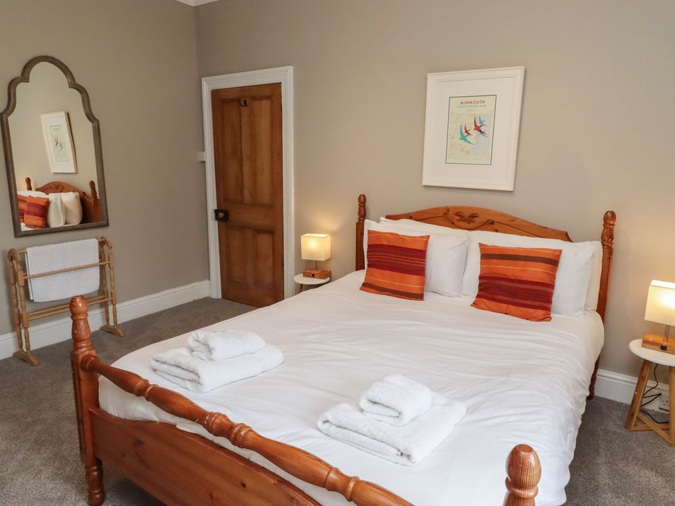 A bedroom with a bed and a mirror at Rose House in Alnmouth