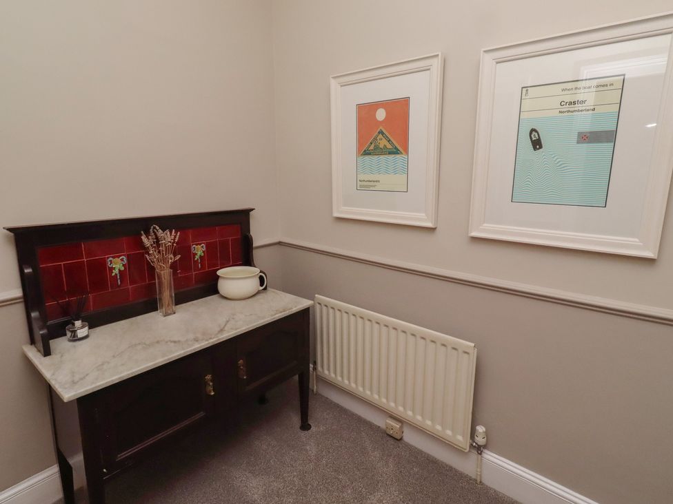 A hallway with a table and framed artwork at Rose House in Alnmouth